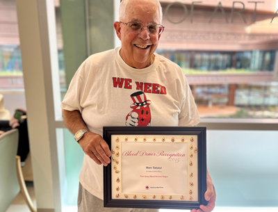 Marc A. Satalof stands with a framed certificate of recognition from the Red Cross.